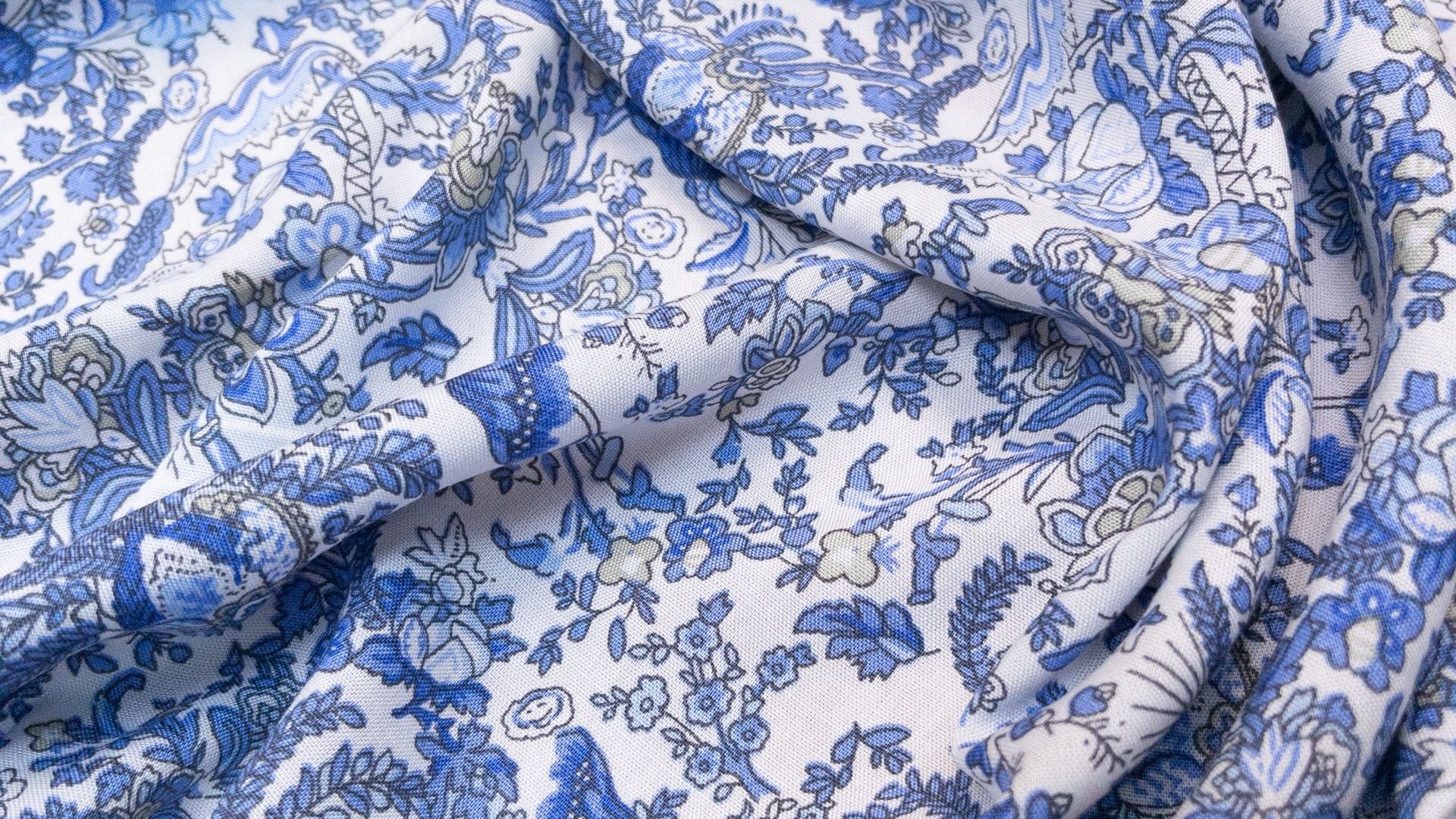 Штапель с нежным голубым цветочным принтом на белом фоне. Нить тонкая, плотно прилегающая, за счет чего полотно тонкое, летящее и совершенно не рыхлое. Подходит для пошива рубашек и легких летних платьев.