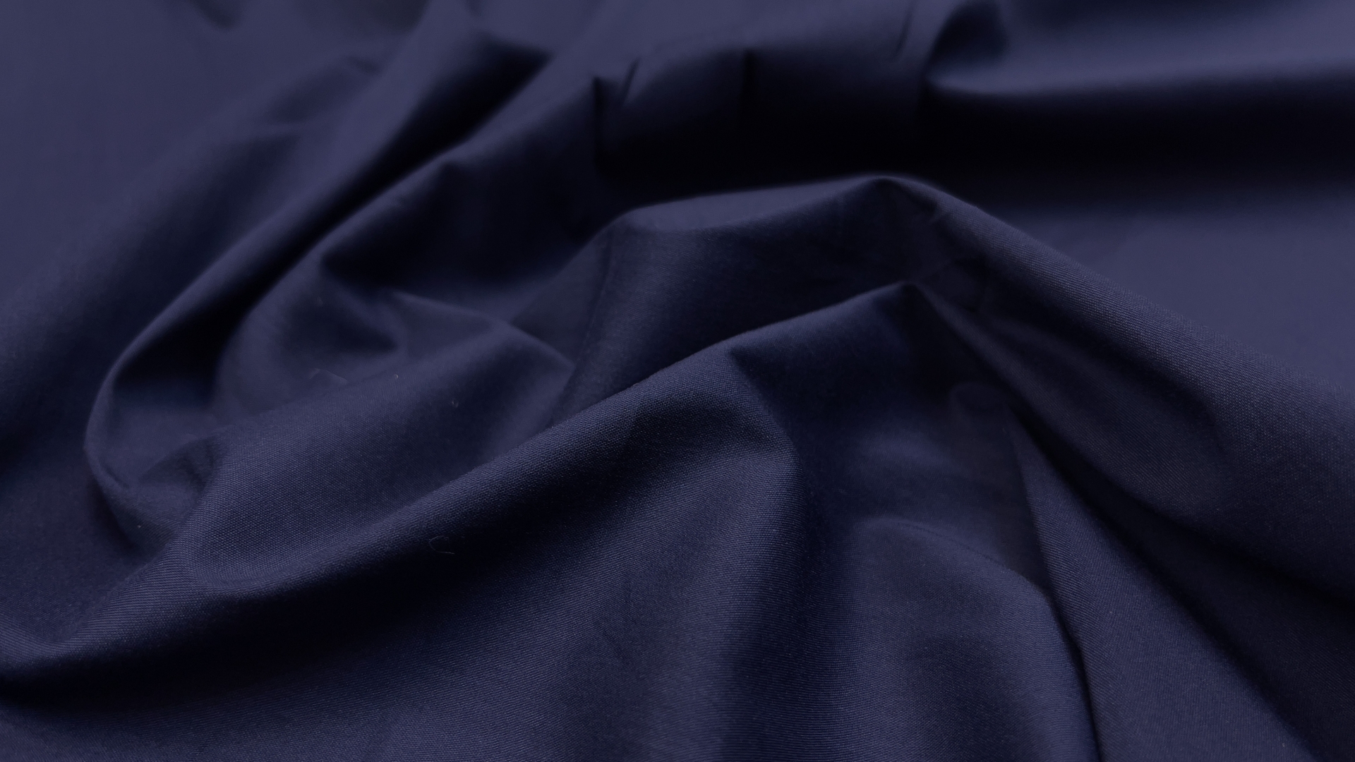 Хлопковый поплин из фабричного стока темно-синего цвета. Плетение очень гладкое, тактильно поплин мягкий. За счет эластана в составе, подойдет для пошива приталенной рубашки. Также хорошо будет смотреться в свободной рубашке-оверсайз.