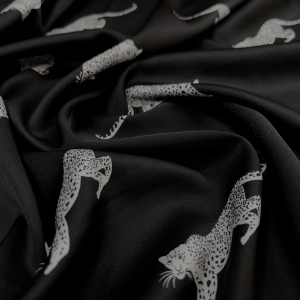 Атлас с торговым названием Армани, на черном фоне белые леопарды. Тактильно атлас очень приятный, мягкий и струящийся. Идеален для пошива рубашки или платья.